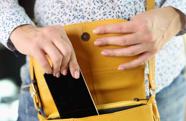 donna mette cellulare in borsa