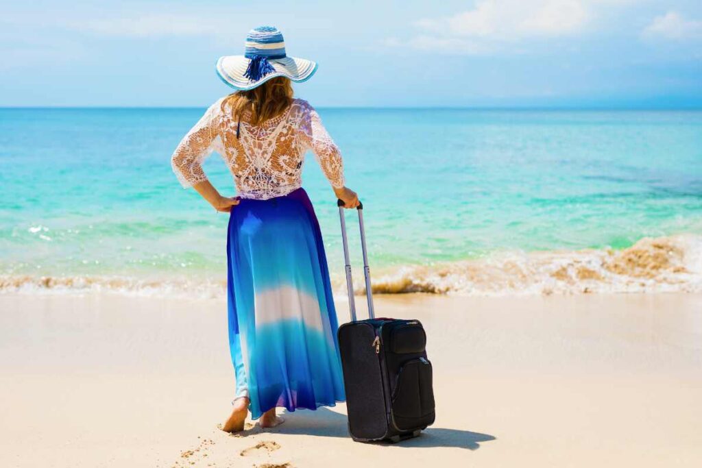 ragazza in spiaggia con valigia